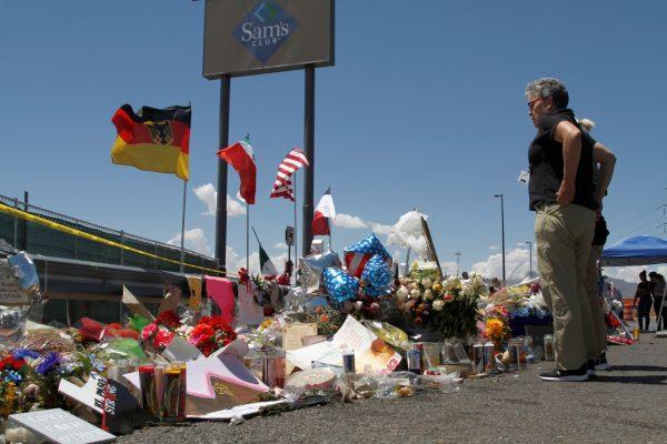 Mourners visit the makeshift memorial near the Walmart where 22 people were killed in a mass shooting in El Paso, Texas, on Aug. 12, 2019. The flags show the nationalities of those killed in the attack, including a German man who lived in nearby Ciudad Juarez, Mexico. (Cedar Attanasio/AP Photo)