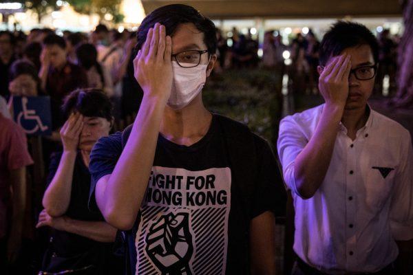 Protesters cover their left eyes and stand in silence during the 74th Liberation Anniversary Assembly in Hong Kong, on Aug. 30, 2019. (Chris McGrath/Getty Images)