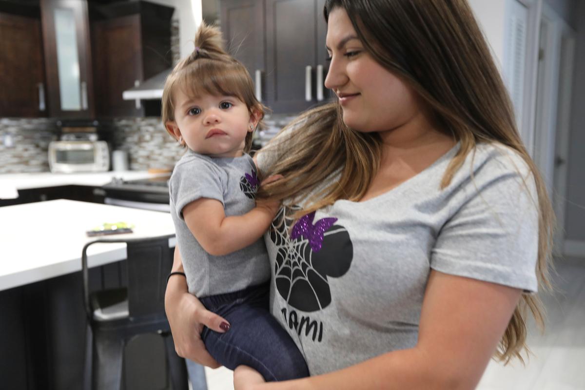 Jessica Armesto holds her one-year-old daughter, Mila's, at their home in Miami, on Aug. 29, 2019. (AP Photo/Marcus Lim)