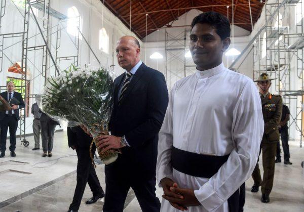 Australia's Home Affairs Minister Peter Dutton (L) holds flowers as Catholic priest Shameera Rodrigo (R) looks on during the Minister's visit to the bombed St Sebastian's Church in Negombo on June 3, 2019. (ISHARA S. KODIKARA/AFP/Getty Images)