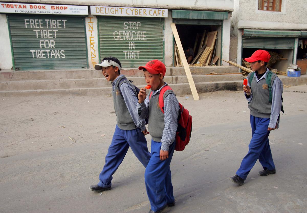 Tibetan students from the Tibetan SOS Children's Village walk home after school past political signs in Choglamsar, Ladakh, India on June 20, 2005. (Paula Bronstein/Getty Images)