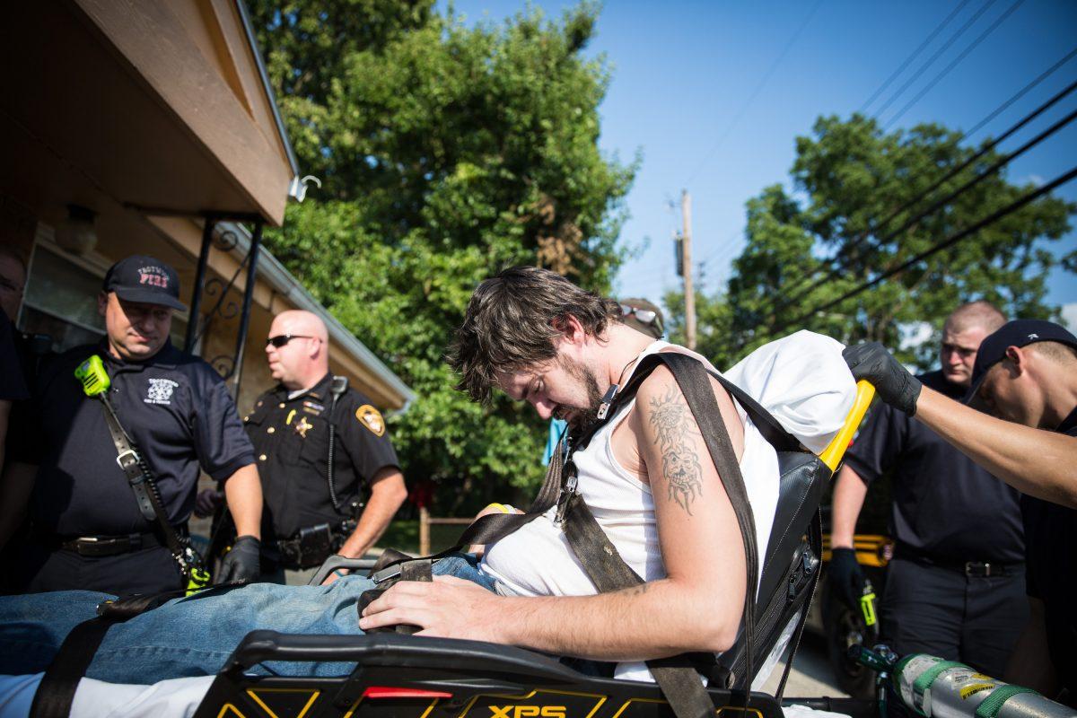 Local police, fire department, and deputy sheriffs help a man who is overdosing in the Drexel neighborhood of Dayton, Ohio, on Aug. 3, 2017. (Benjamin Chasteen/The Epoch Times)