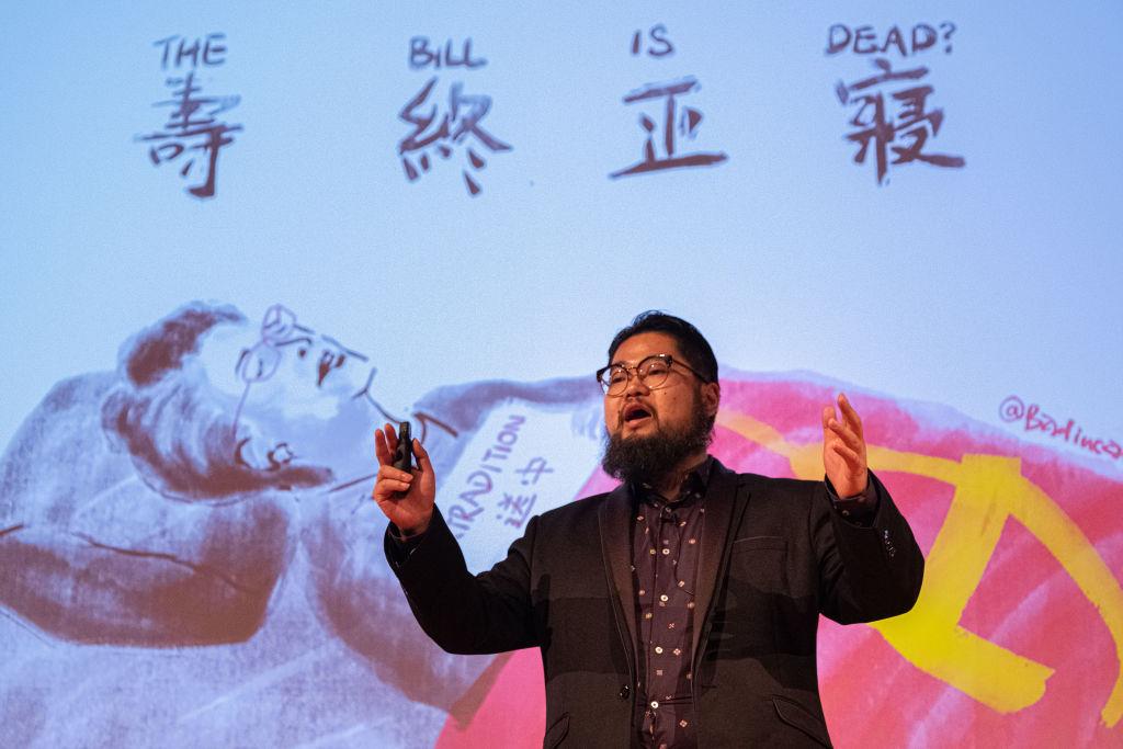 Chinese political cartoonist Badiucao speaks in front of one his satirical illustrations of Hong Kong Chief Executive Carrie Lam, titled 'Is the Bill Dead,' during an event at the Melbourne City conference centre in Australia on September 04, 2019. The event was held to discuss the current crisis in Hong Kong and the future of the city. (Asanka Ratnayake/Getty Images)