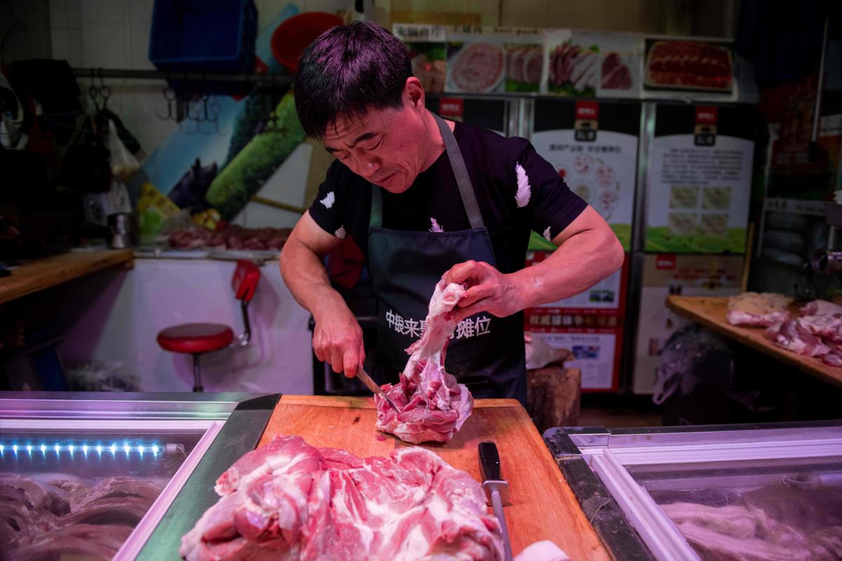 A butcher cuts a piece of pork meat at his stall at a market in Beijing, China, on July 10, 2019. (Nicolas Asfouri/AFP/Getty Images)