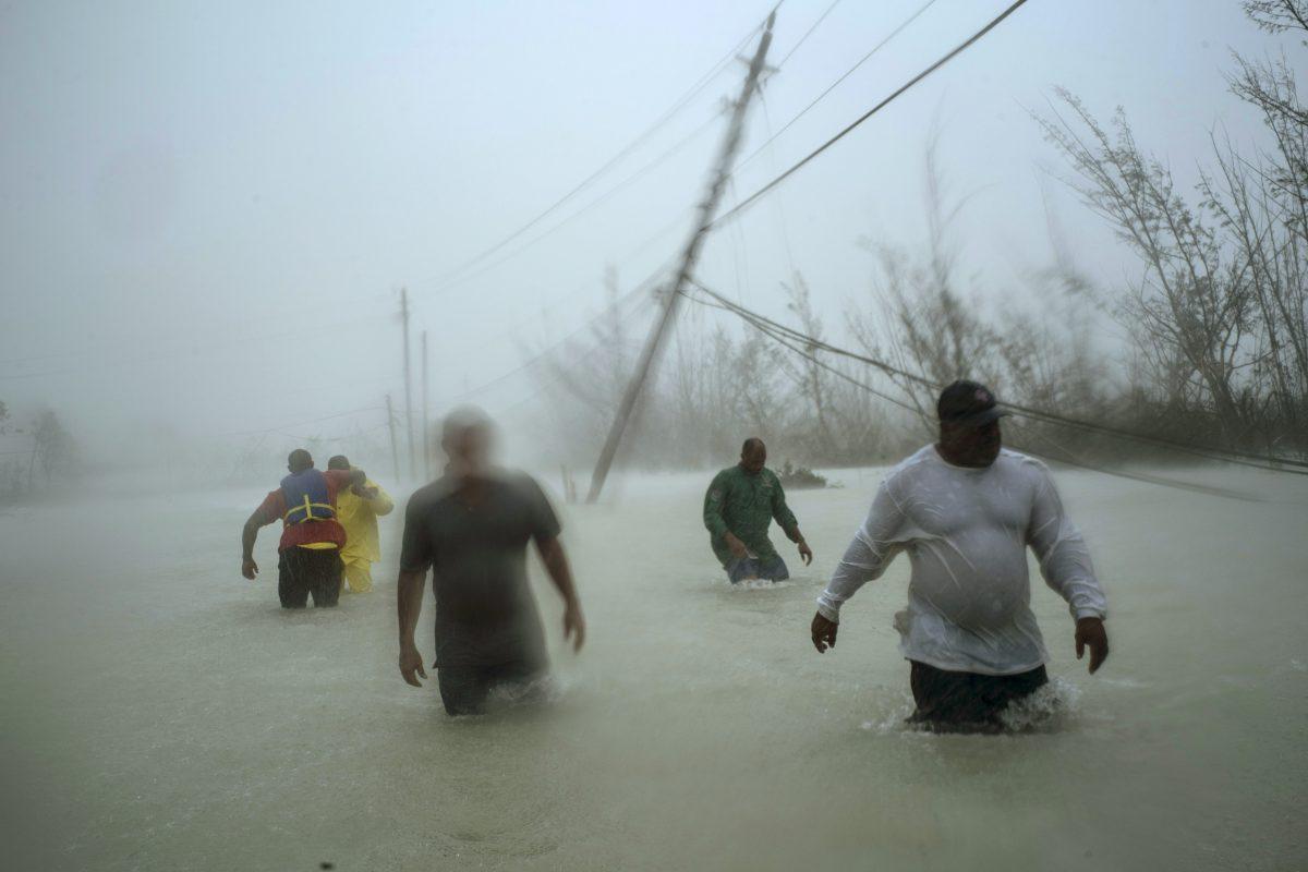 Volunteers walk under the wind and rain from Hurricane Dorian through a flooded road as they work to rescue families near the Causarina bridge in Freeport, Grand Bahama, Bahamas, on Sept. 3, 2019. (AP Photo/Ramon Espinosa)