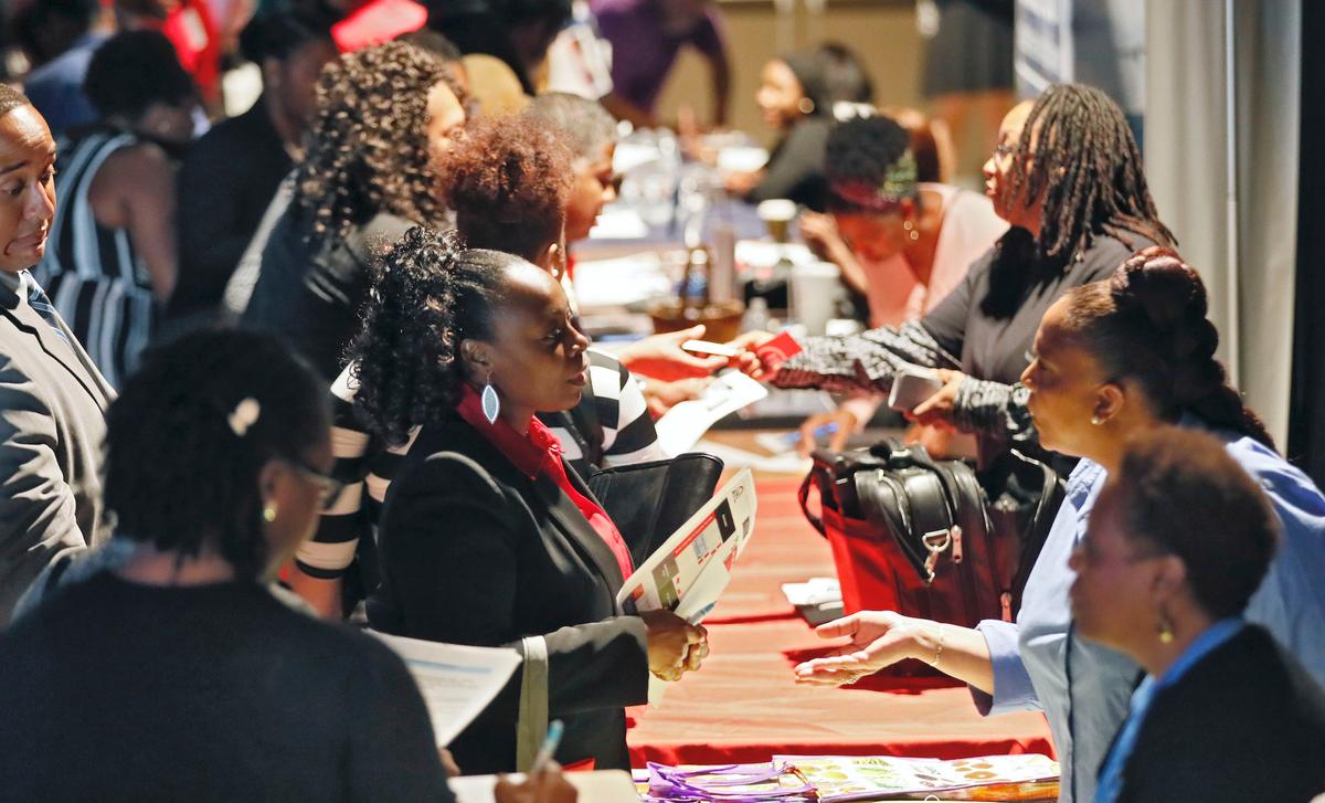 File photo company representatives from Verizon, Goodwill, Kaiser Permanente and UPS, right, talk with potential applicants during a job and resource fair in Atlanta. (Bob Andres/Atlanta Journal-Constitution via AP/File)