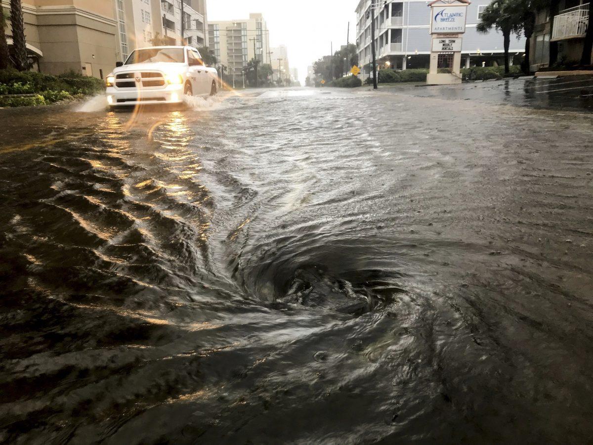 Floodwaters swirl around a storm drain as heavy rain falls from Hurricane Dorian in North Myrtle Beach, S.C., on Sept. 5, 2019. (Jason Lee/The Sun News via AP)