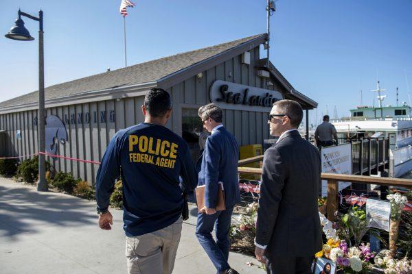 Federal agents walk past a memorial for the victims of the Conception dive boat fire on the Santa Barbara Harbor in Santa Barbara, Calif., on Sept. 8, 2019. (Christian Monterrosa/AP Photo)