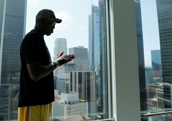Former NBA player Dennis Rodman is silhouette next to the skyline of Los Angeles as he poses for a portrait in Los Angeles, on Sept. 9, 2019. (Mike Blake/Reuters)