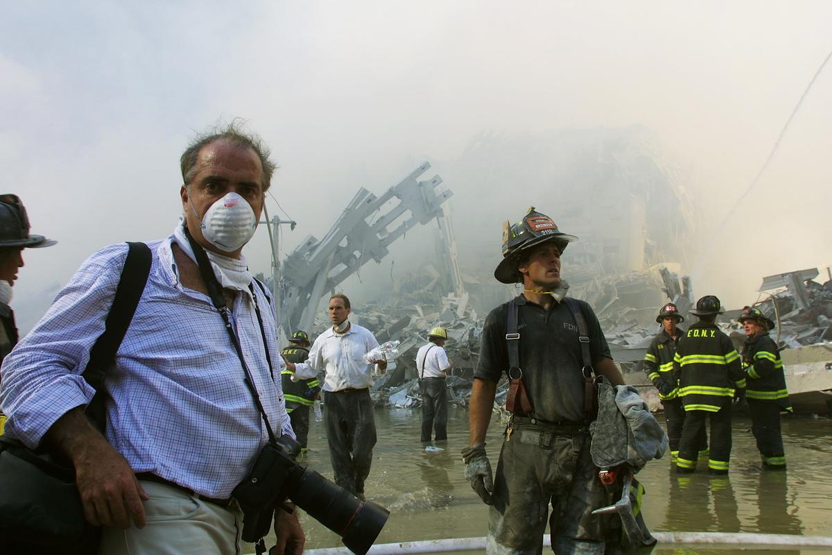 New York City firefighters and a photojournalist work at the World Trade Center after two hijacked planes crashed into the Twin Towers in New York City on Sept. 11, 2001. (Ron Agam/Getty Images)