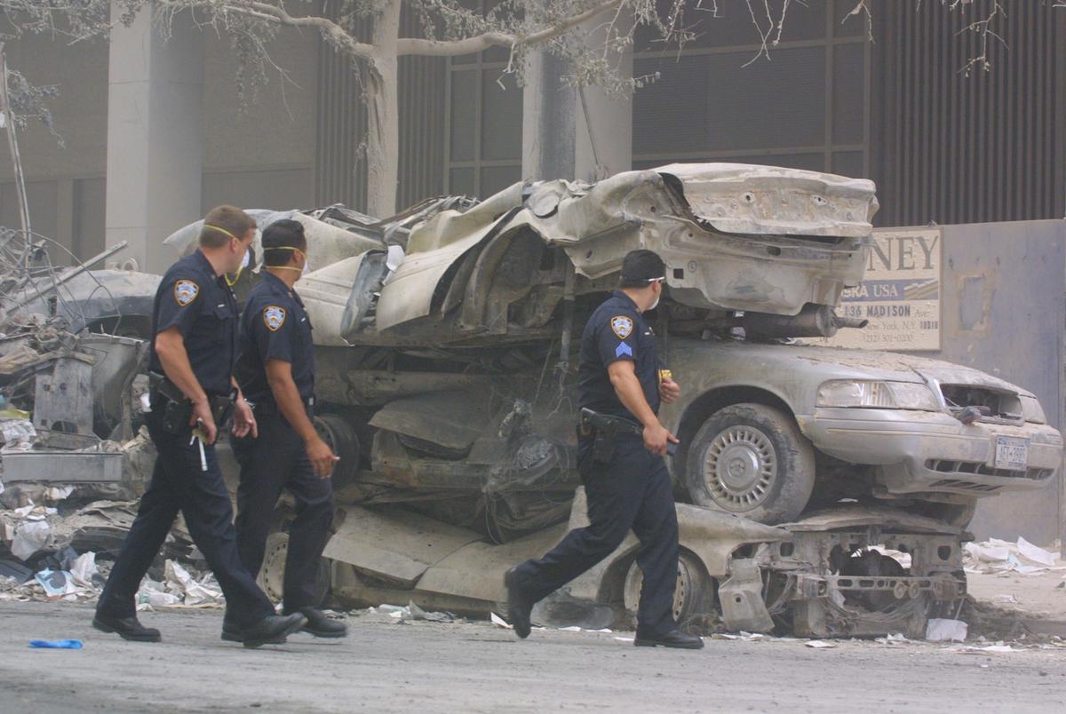 Policemen walk past crushed cars near the wreckage of the World Trade Center in New York City on Sept. 13, 2001. Rescue efforts continued two days after two highjacked airplanes slammed into the twin towers in a terrorist attack, leveling them. (Mario Tama/Getty Images)