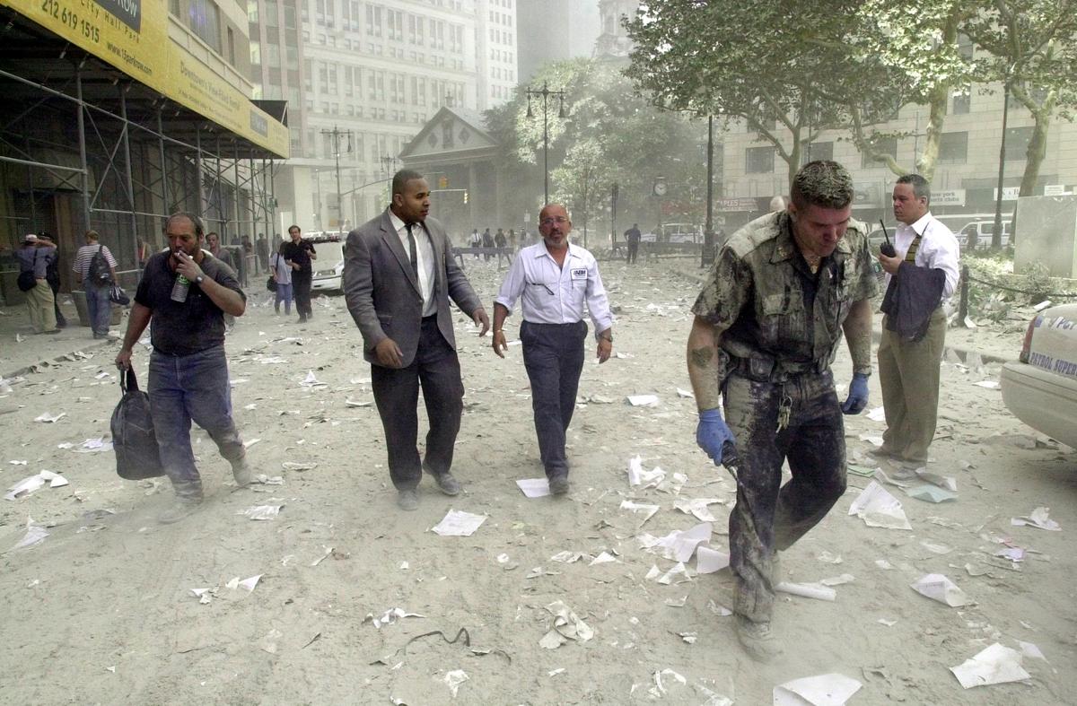 A police officer (R) and others walk in the streets covered in debris near the World Trade Center towers in New York on Sept. 11, 2001. Two planes crashed into each building and the tops of each tower collapsed. (Stan Honda/AFP/Getty Images)