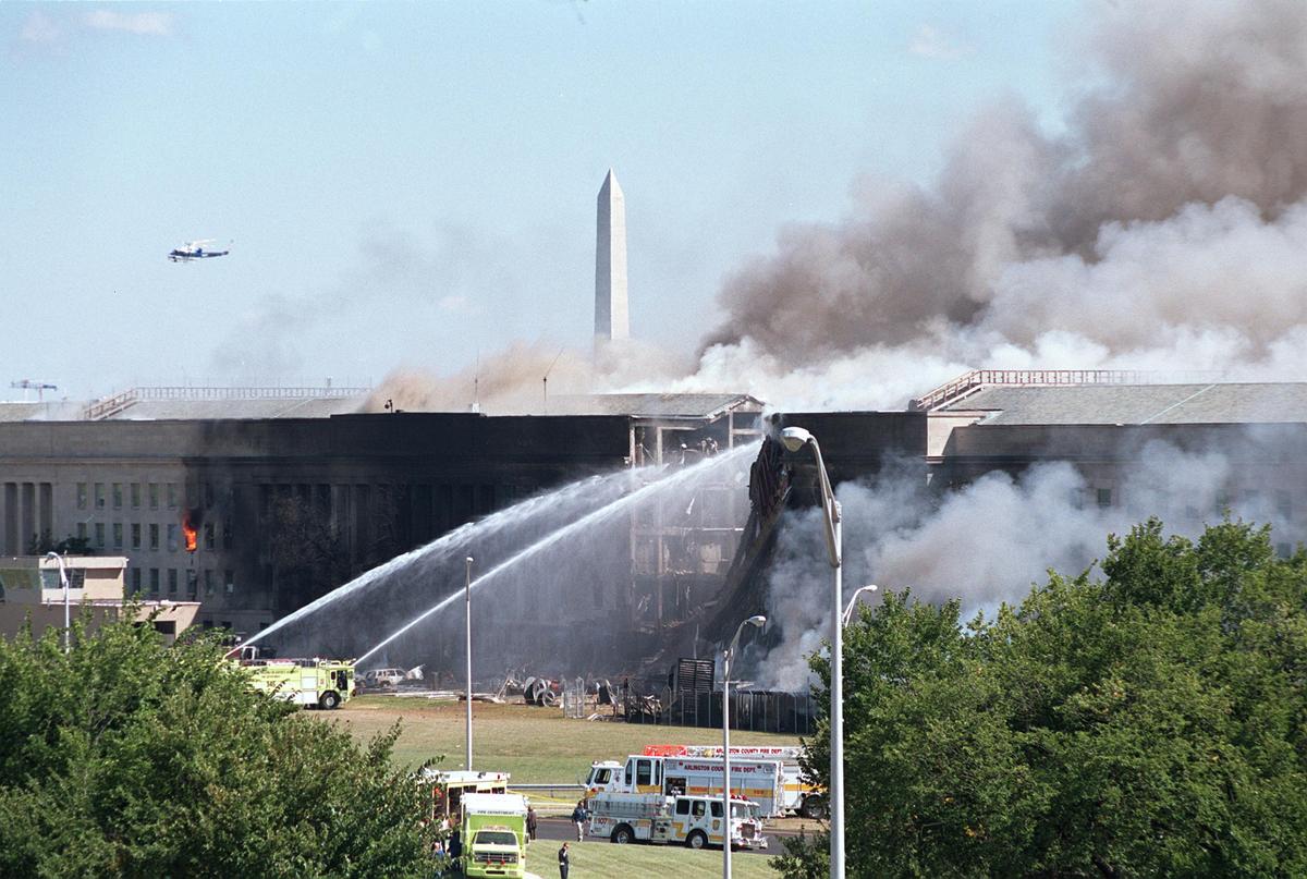 The Washington Monument stands in the background as firefighters pour water on a fire at the Pentagon that was caused by a hijacked plane crashing into the building in Washington on Sept. 11, 2001. (Greg Whitesell/Getty Images)