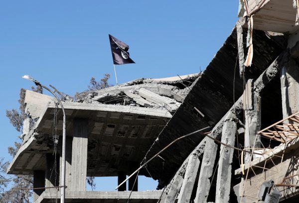 A flag of the ISIS terror group pictured above a destroyed house near the Clock Square in Raqqa, Syria, on Oct. 18, 2017. (Erik De Castro/Reuters)