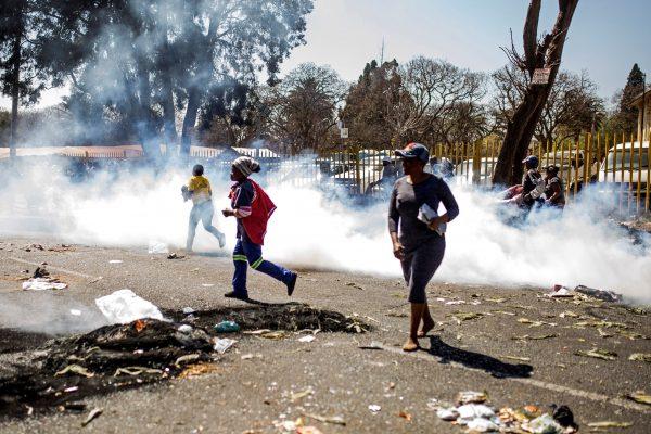 South African looters run through tear gas smoke during a riot in the Johannesburg suburb of Turffontein on Sept. 2, 2019 as angry protesters loot alleged foreign-owned shops in a new wave of violence targeting foreign nationals. (Guillem Sartotrio/AFP/Getty Images)