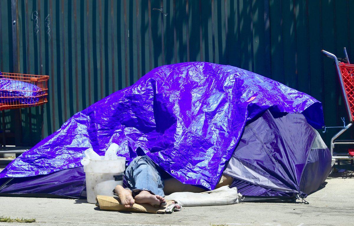 A homeless person sleeps beneath a tarp covering a tent lining sidewalks in downtown Los Angeles, California on April 20, 2017. (Frederic J. Brown/AFP/Getty Images)