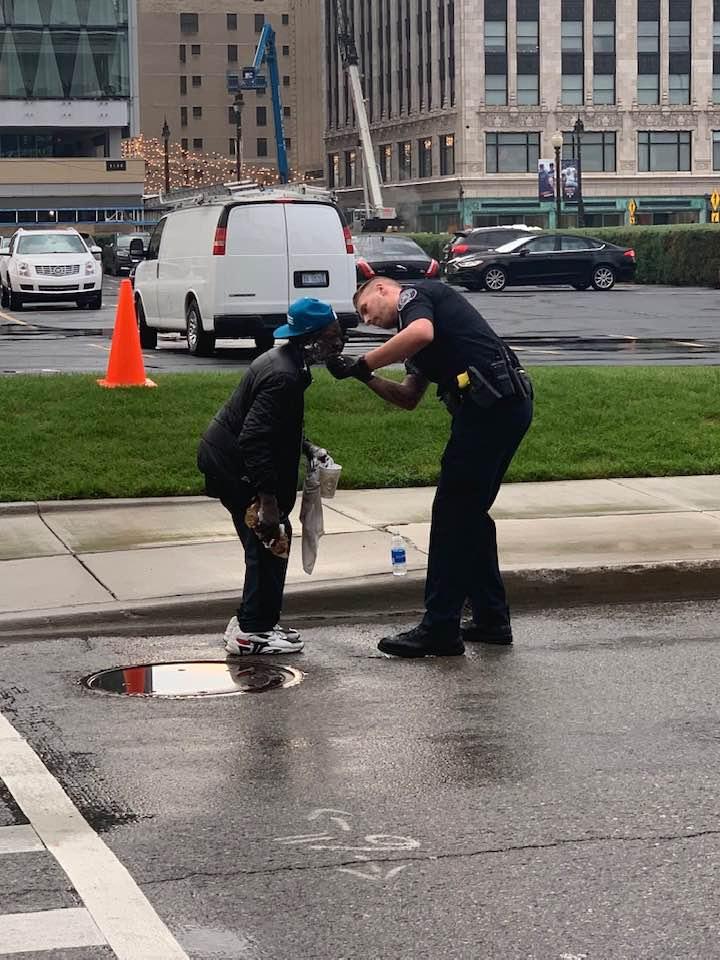 A police officer helps a man shave outside of Comerica Park in Detroit, Michigan on Sept. 11, 2019. (Courtesy of Jill Metiva Schafer)