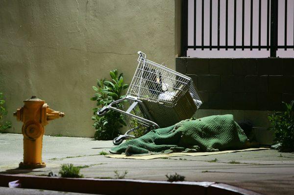 In this file image a homeless person sleeps by his shopping cart on a downtown sidewalk in the early morning hours of April 19, 2006, in Los Angeles, Calif. (David McNew/Getty Images)
