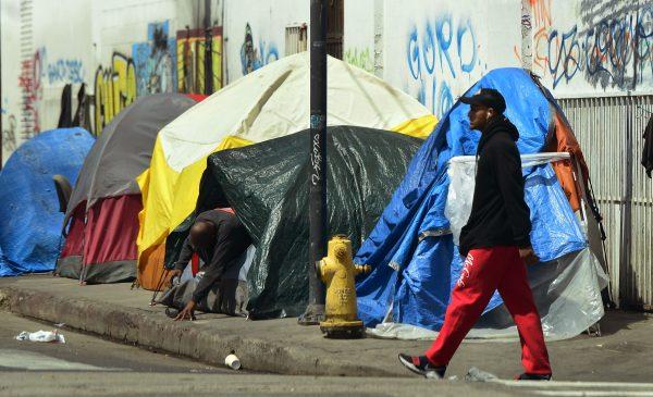 A person makes his way out of his tent among a row of tents along a sidewalk in downtown Los Angeles on May 30, 2019. (Frederic J. Brown/AFP/Getty Images)