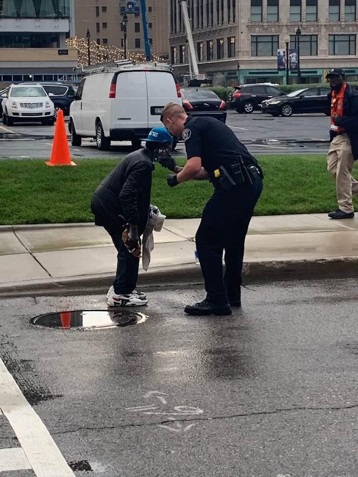A police officer helps a man shave outside of Comerica Park in Detroit, Michigan on Sept. 11, 2019. (Courtesy of Jill Metiva Schafer)