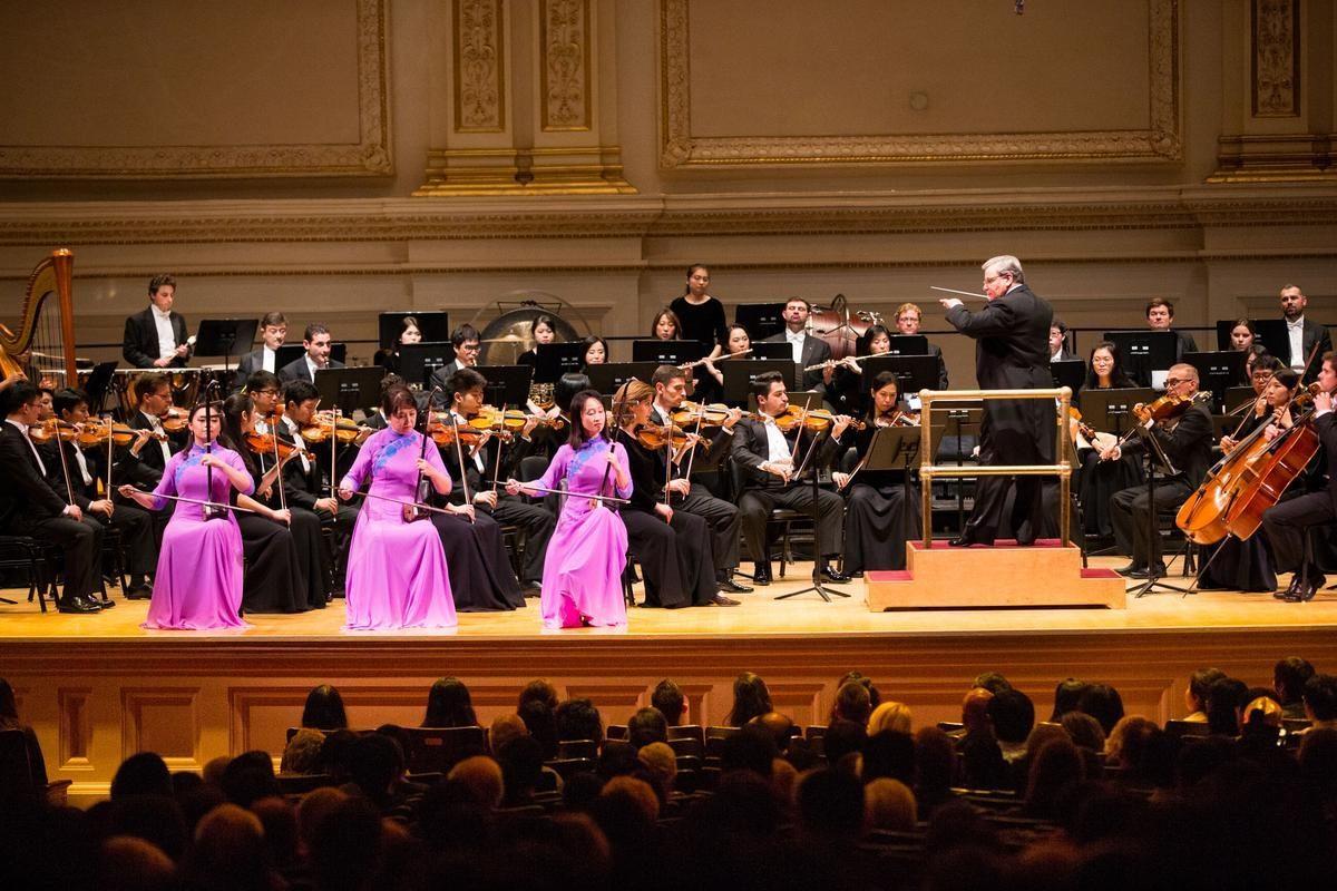 Three erhu players are accompanied by the Shen Yun Symphony Orchestra. (Dai Bing/The Epoch Times)