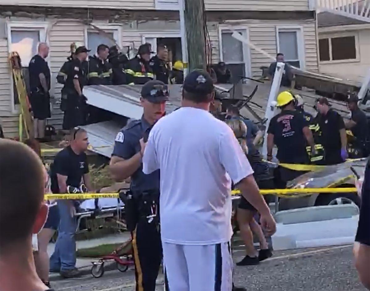 In this photo provided by James Macheda, one of the first responders talks to an onlooker as others carry an injured person, while some others work the scene of a building structure damage, in the background, in Wildwood, N.J., Saturday, Sept. 14, 2019. Multiple levels of decking attached to a building collapsed Saturday evening at the Jersey Shore, trapping people and injuring several, including children, officials and witnesses said. (James Macheda via AP)