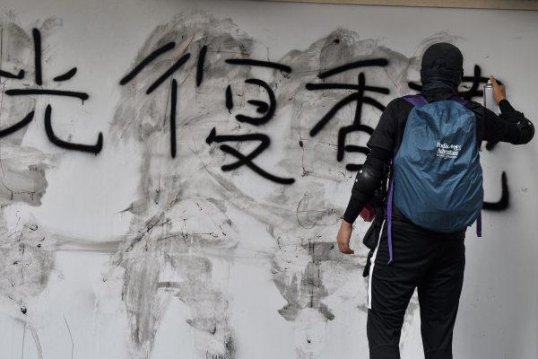 A protester sprays graffiti on a wall that reads "Reclaim Hong Kong" during a pro-democracy march in Hong Kong on Sept. 15, 2019. (Nicolas Asfouri/AFP/Getty Images)