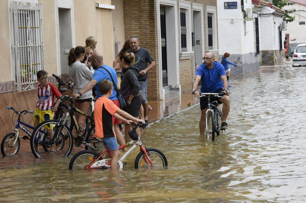 People ride bicycles along a flooded street after heavy raining in El Raal, near Murcia, Spain, on Sept. 14, 2019. (Alfonso Duran/AP Photo)