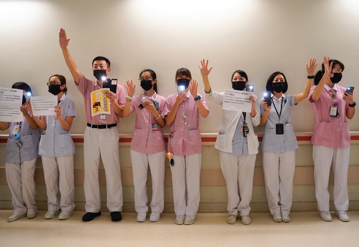 Medical workers display opened palm with five fingers, signifying the five demands of protesters and chanted slogans as they stood in the foyer of the hospital before moving to different floors of the building at the Prince of Wales Hospital in Hong Kong on Sept. 16, 2019. (Vincent Yu/AP)
