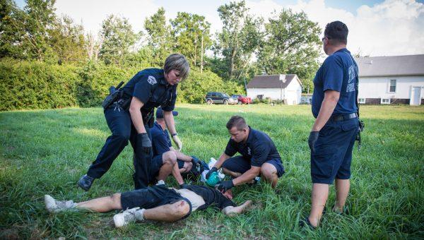 Local police and paramedics help a man who is overdosing in the Drexel neighborhood of Dayton, Ohio, on Aug. 3, 2017. It's unclear what he overdosed on. (Benjamin Chasteen/The Epoch Times)