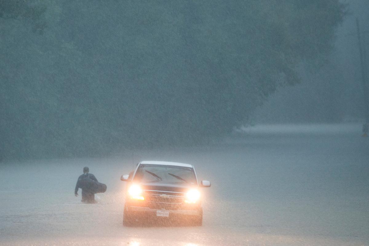 A man walks into high water into his neighborhood as rain from Tropical Depression Imelda inundated the area on Sept. 19, 2019, near Patton Village, Texas. (Brett Coomer/Houston Chronicle via AP)