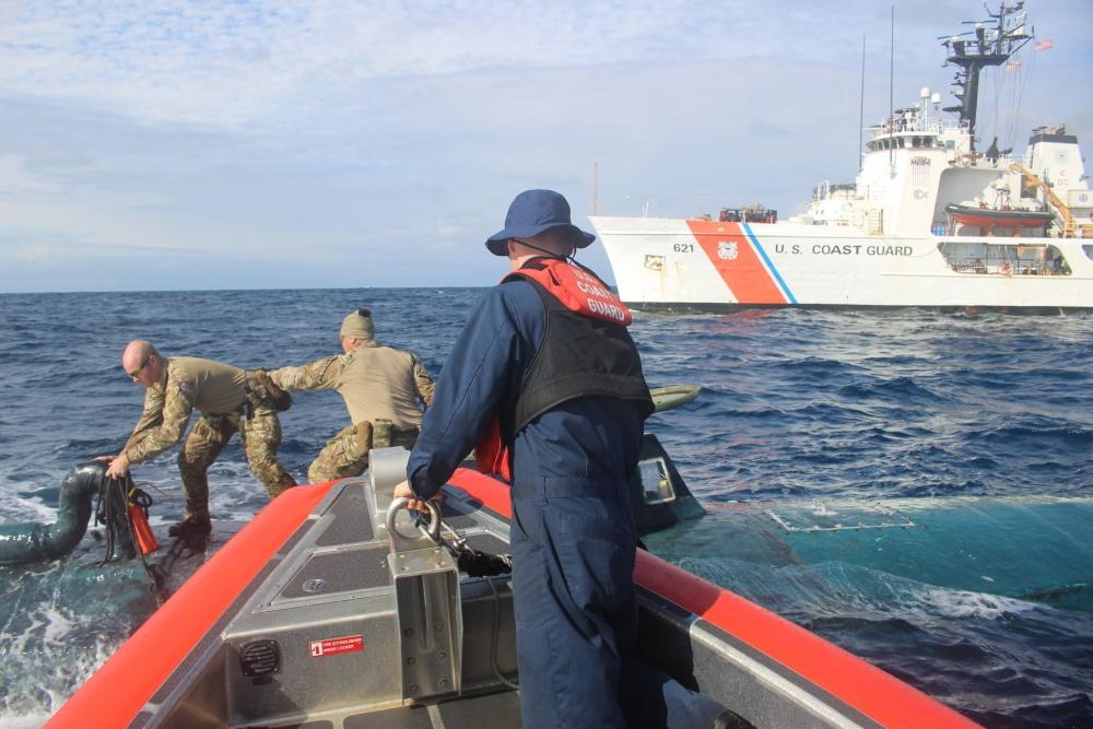 Members of a U.S. Coast Guard Cutter Valiant boarding team transfer narcotics between an interceptor boat and a suspected smuggling vessel in Sept. (U.S. Coast Guard Photo)