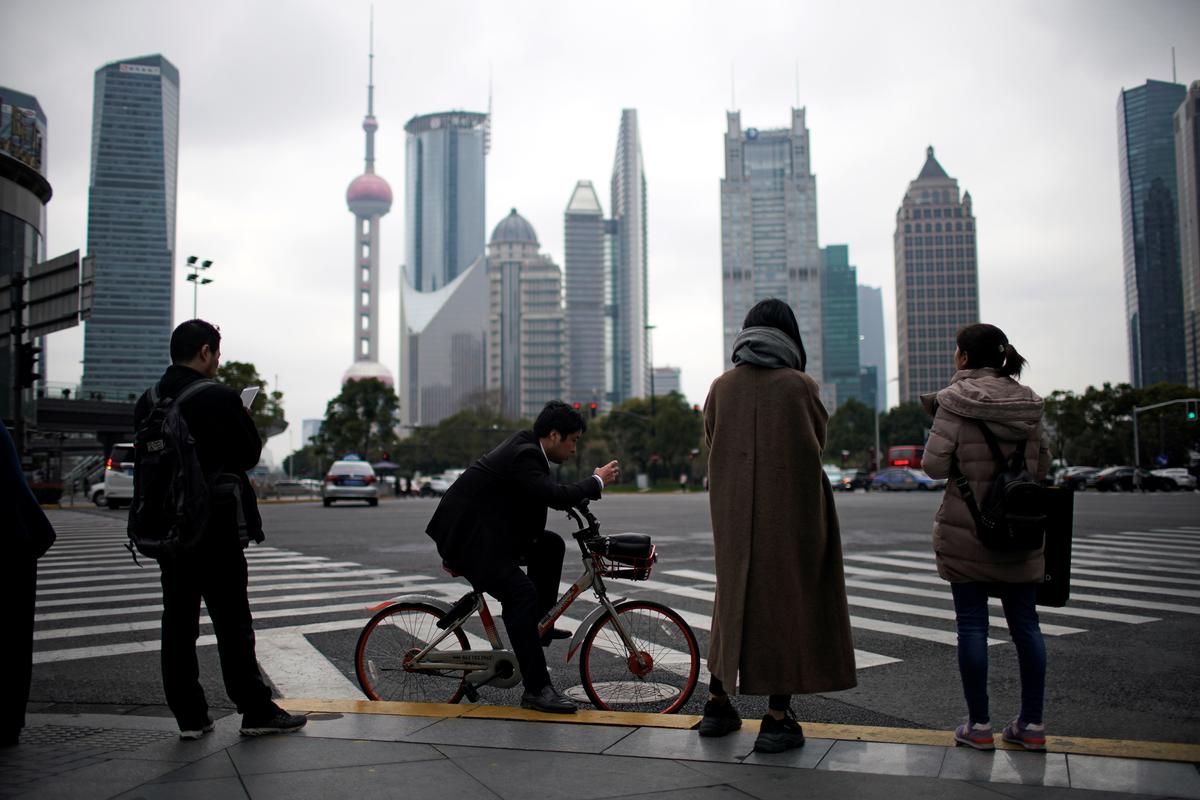 People stand on the sidewalk at Lujiazui financial district in Pudong, Shanghai, China, on March 14, 2019. (Aly Song/Reuters)