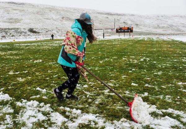 Ne'vaeh Allison clears snow from the Centerville High School football field before the school's game against Belt High in Centerville, Mont., on Sept. 28, 2019. (Rion Sanders/The Great Falls Tribune via AP)