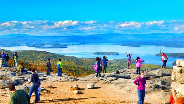 Tourists posing for photos at the summit of Mount Major in New Hampshire in 2015. Lake Winnipesaukee and the Belknap Mountains can be seen in the background. (Gettyimages)