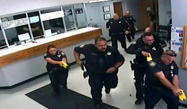 Photo taken from surveillance video posted on Twitter and released by the Salinas Police Department shows officers chase a woman who had taken another woman hostage on Sept. 25, 2019, then ran out the front door of the lobby of the Salinas Police Department in Salinas, Calif. (Salinas Police Department via AP)