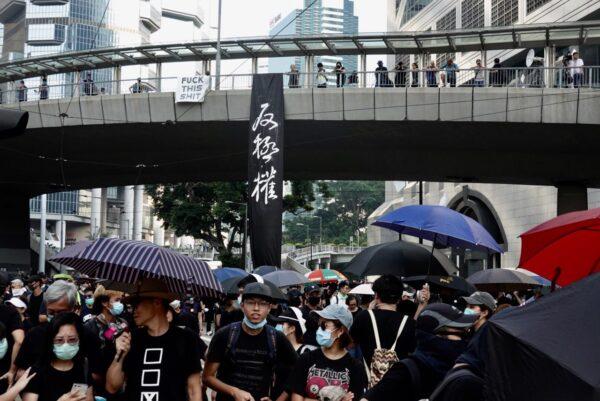 Hong Kong protesters march through a skybridge with a banner that reads: "Oppose authoritarian rule," on Oct. 1. (Sung Pi Lung/The Epoch Times)