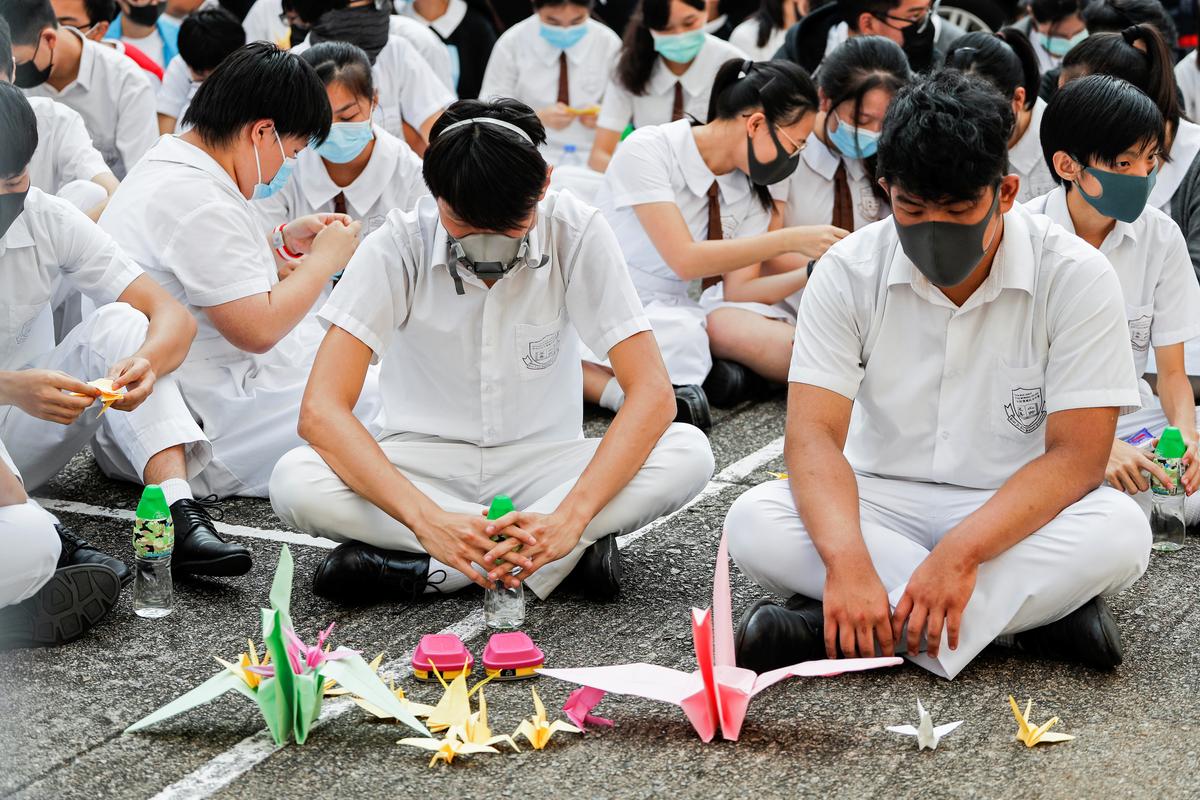 Schoolmates of a student protester who was shot by a policeman on Oct. 1 sit beside paper cranes while participating in a student gathering at Tsuen Wan Public Ho Chuen Yiu Memorial College in solidarity with the student in Tsuen Wan, Hong Kong, China on Oct. 2, 2019. (Susana Vera/Reuters)