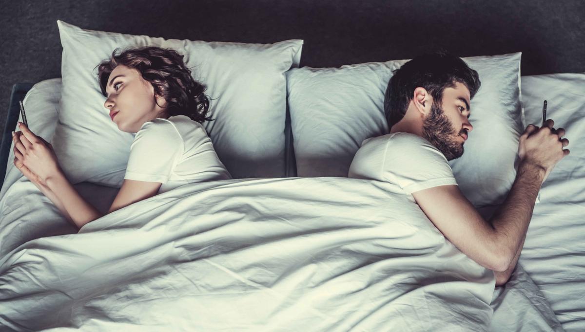Illustration - Shutterstock | <a href="https://www.shutterstock.com/image-photo/young-couple-bed-using-phone-lying-639801664">VGstockstudio</a>