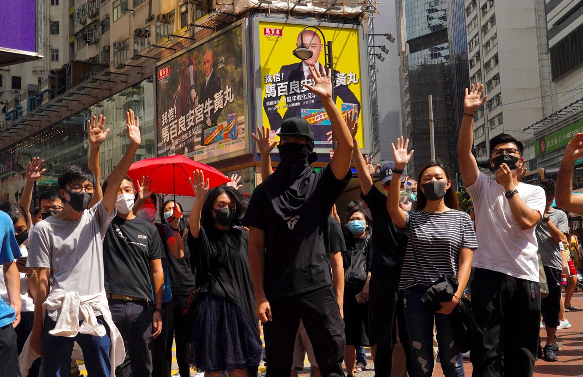 Protesters wear masks and hold up their hands to represent their five demands in Hong Kong on Oct. 4, 2019. (Vincent Yu/AP)
