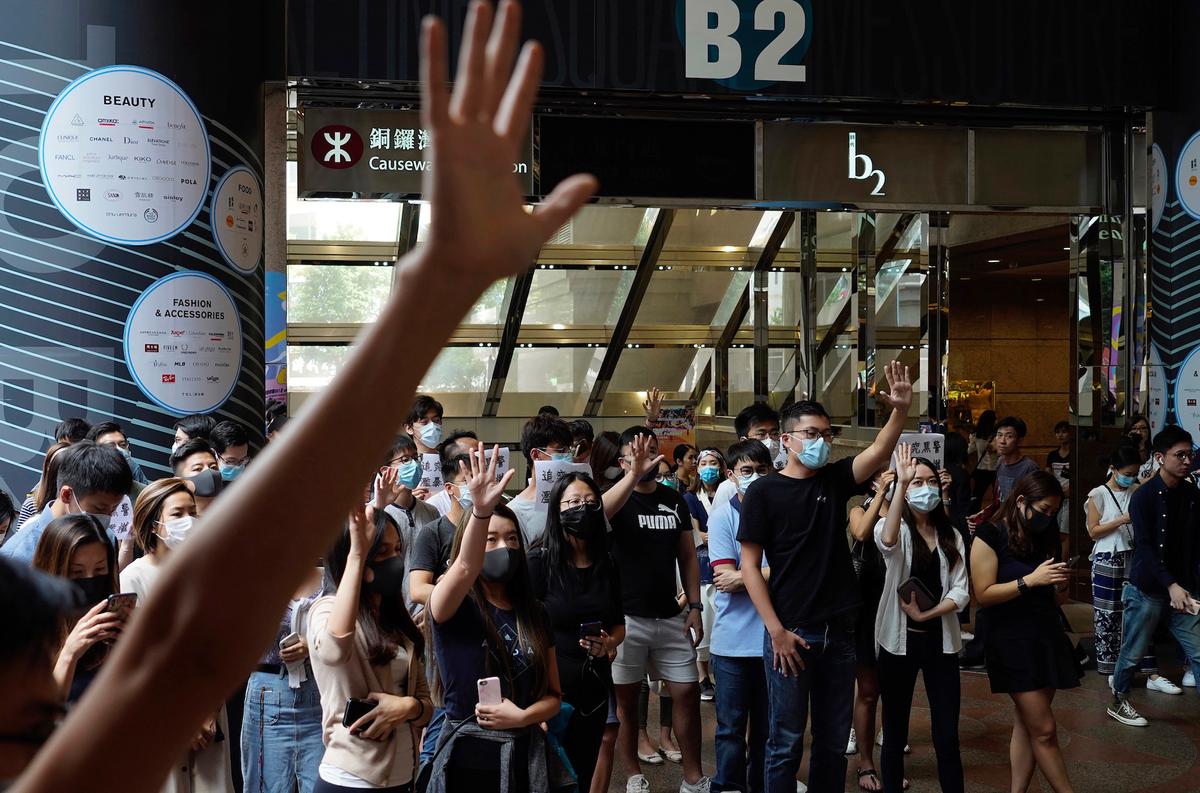 Protesters wear masks and hold up their hands to represent the protesters' five demands in Hong Kong on Oct. 4, 2019. (Vincent Yu/AP)