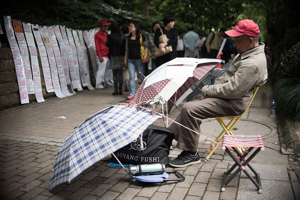 Parents looking for partners for their children at a marriage market in Shanghai on May 30, 2015 (©Getty Images | <a href="https://www.gettyimages.com/detail/news-photo/chinese-man-sleeps-as-people-walk-past-advertising-notices-news-photo/475220404?adppopup=true">Joannes Eisele</a>)