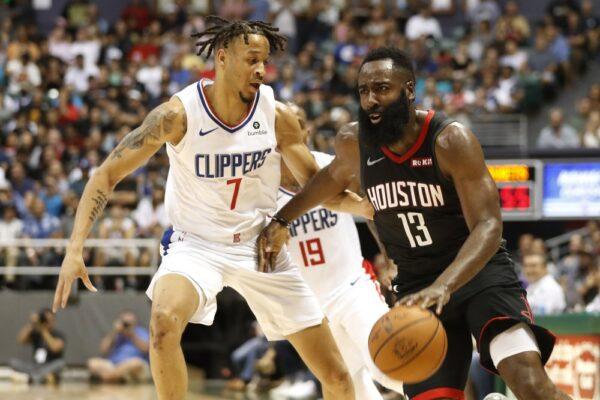 Los Angeles Clippers shooting guard Amir Coffey (7) guards Houston Rockets shooting guard James Harden (13) during the second quarter of an NBA preseason basketball game, in Honolulu, Hawaii. (AP Photo/Marco Garcia)