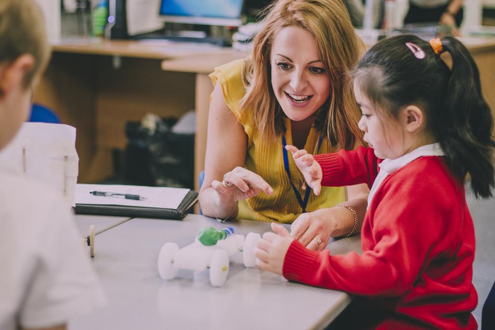 Illustration - Shutterstock | <a href="https://www.shutterstock.com/image-photo/teacher-sitting-table-her-classroom-primary-634019516?src=w0Sf7zLXizW9xr-P3pM5xQ-1-0">DGLimages</a>