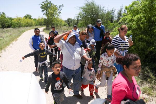 A group of illegal aliens walk up the road after crossing the Rio Grande from Mexico, near McAllen, Texas, on April 18, 2019. (Charlotte Cuthbertson/The Epoch Times)