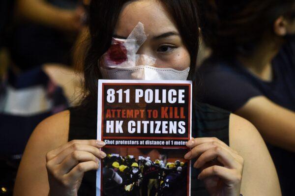 An anti-extradition bill protester holds a sign against police brutality during a gathering at Chater House Garden in Hong Kong on Aug. 16, 2019. (Lillian Suwanrumpha/AFP/Getty Images)