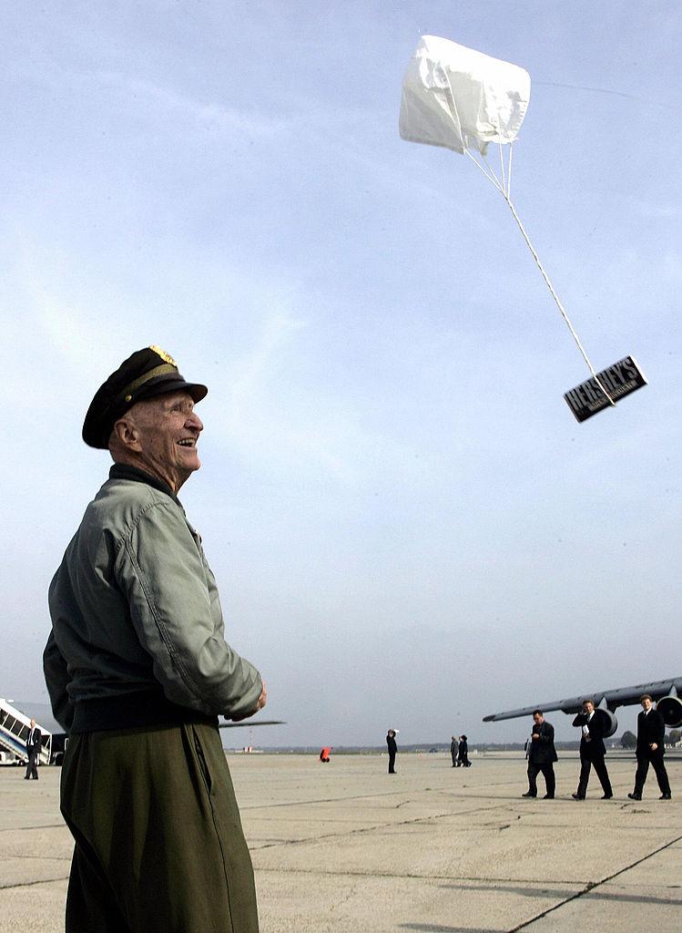 Gail S. Halvorsen, former U.S. pilot of a so-called "Candy Bomber," flies a bar of chocolate attached on a little parachute on Oct. 10, 2005, at the military airbase in Frankfurt/Main, after the handing over of the base to the Federal Republic of Germany. (TORSTEN SILZ/DDP/AFP via Getty Images)