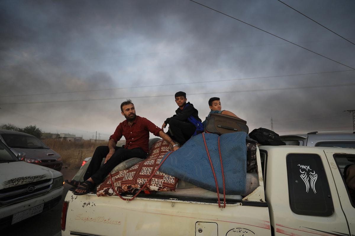 People sit on belongings at a back of a truck as they flee Ras al Ain town, Syria Oct. 9, 2019. (Reuters/Rodi Said)