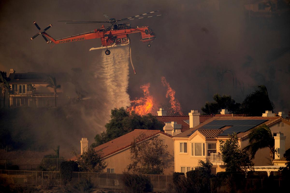 A helicopter drops water while battling the Saddleridge Fire in Porter Ranch, Calif., on Friday, Oct. 11, 2019. (AP Photo/Noah Berger)