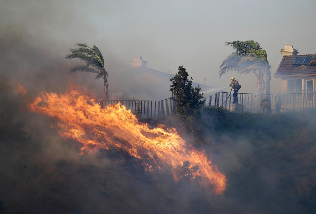 A firefighter sprays water in front of an advancing wildfire, in Porter Ranch, California, on Oct. 11, 2019. (AP Photo/Marcio Jose Sanchez)